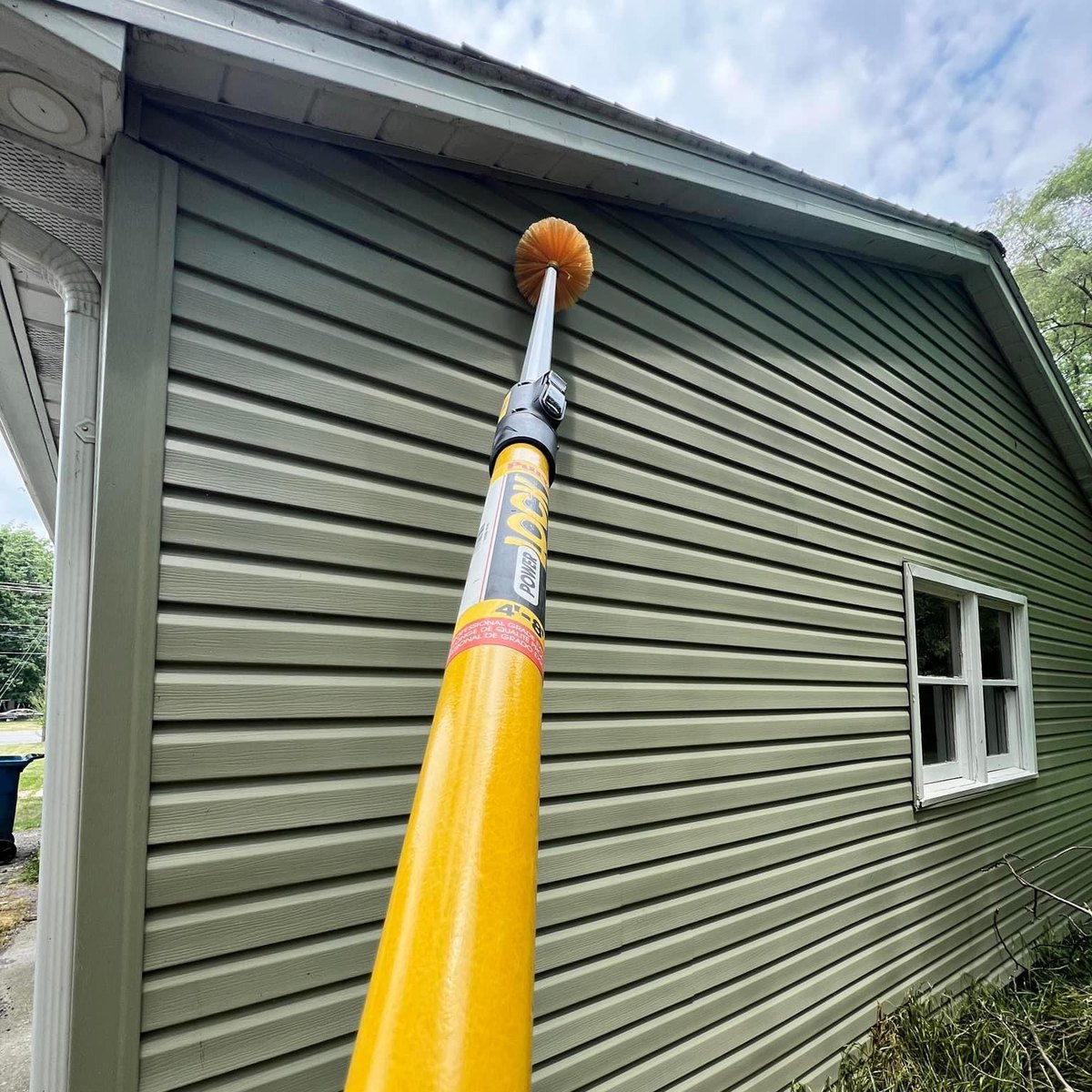 DeadOne technician clearing webs from the siding and eaves of a home